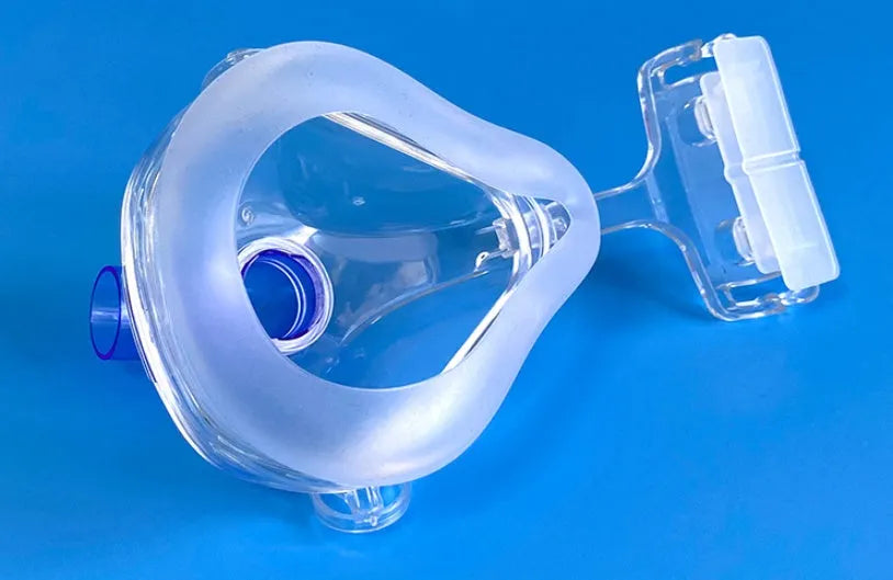 Transparent CPAP breathing mask with silicone seal, headgear, and two polycarbonate adapter elbows for ventilator connection.