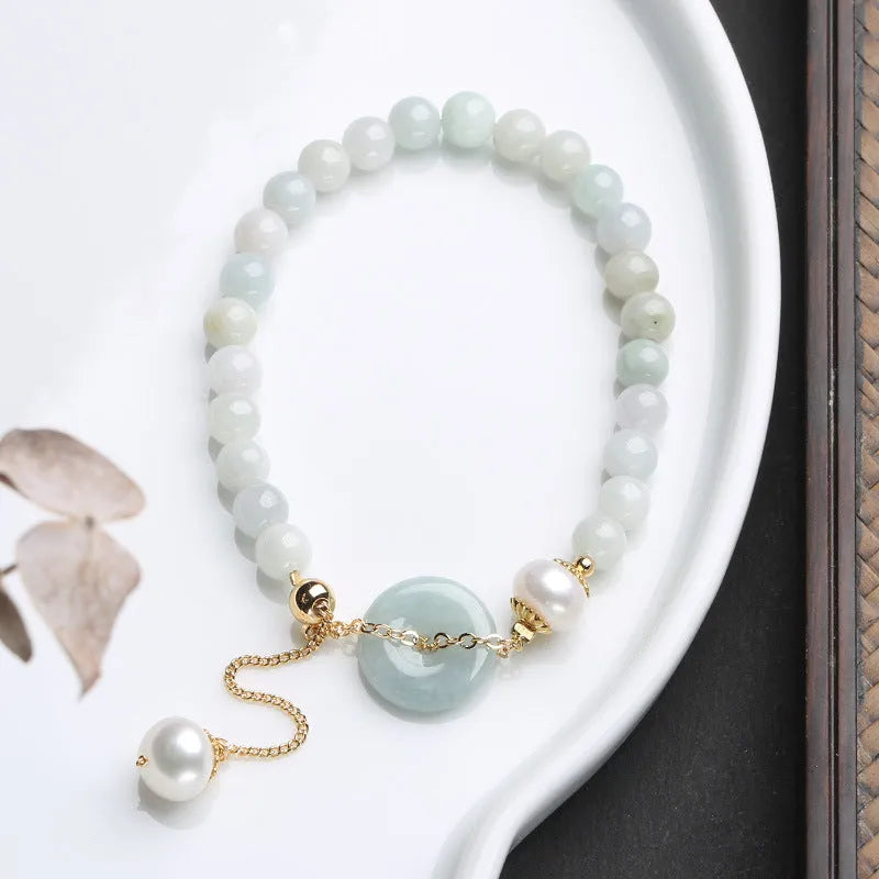 Green jade peace buckle charm and pearl beaded bracelet for women on a white background.