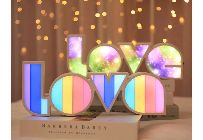 Rainbow-coloured plastic LED light spelling LOVE, standing 35.5cm tall on a table.