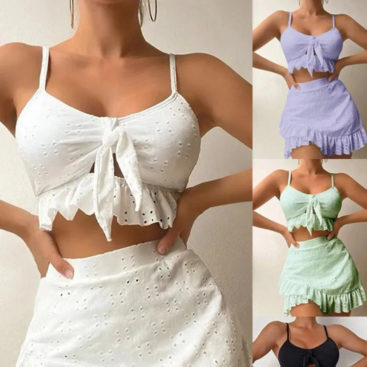 Women's white three-piece bikini swimsuit with a split hip skirt laid flat.