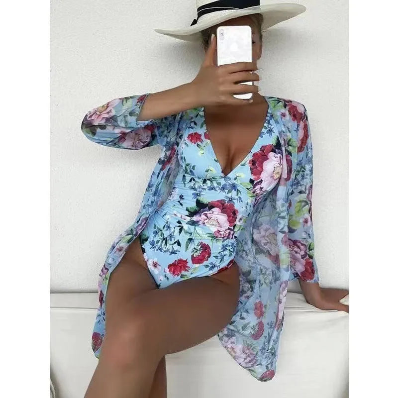 Women's floral print three-piece bikini set with a cover-up coat on a hanger