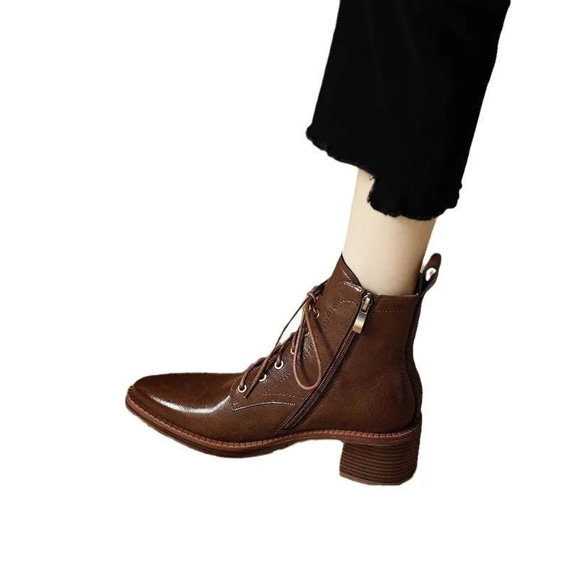 Women's black pointed-toe ankle boots with a short tube and block heel on a plain background