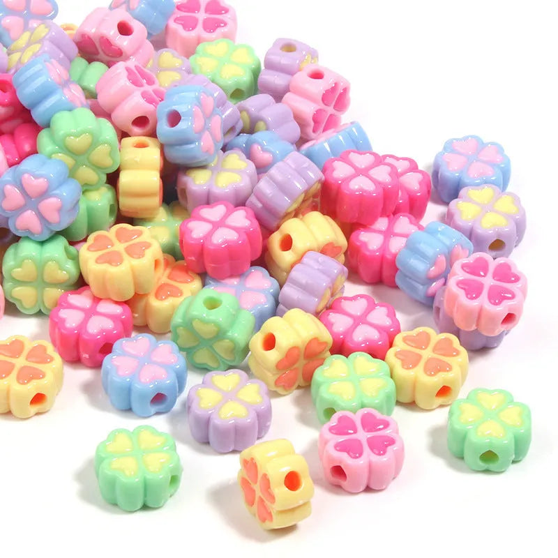 A selection of 15mm frosted acrylic beads in various colours, each showing a four-leaf clover love pattern.