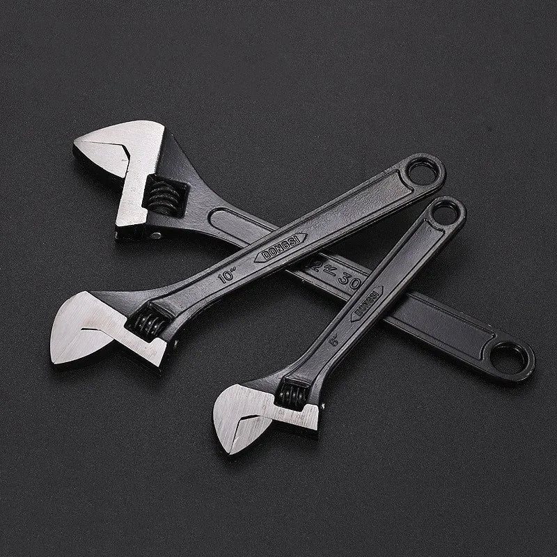High carbon steel adjustable open-end spanner with black finish on a workbench.