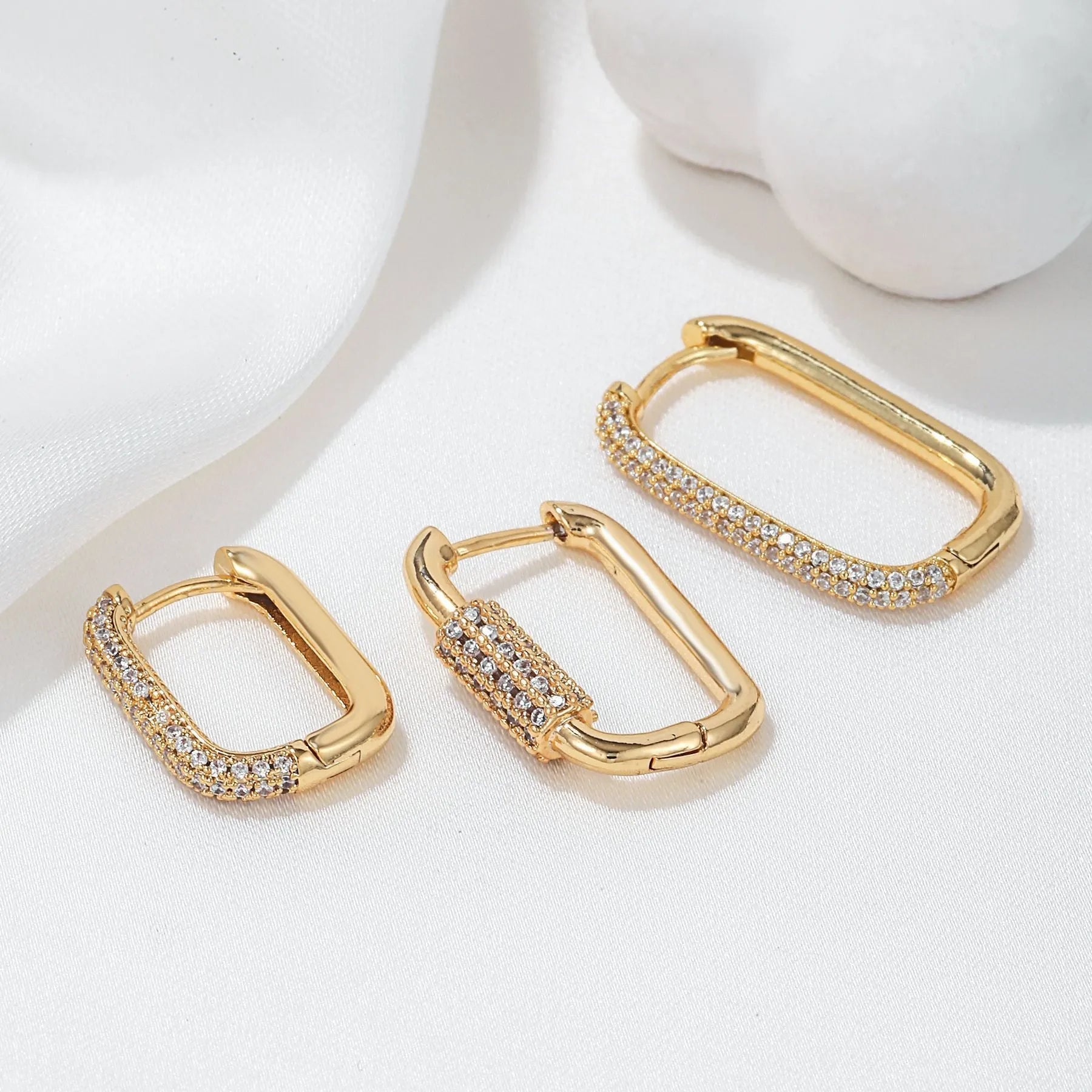 Three geometric copper ear clips with micro inlaid zircon detailing in gold and white finishes
