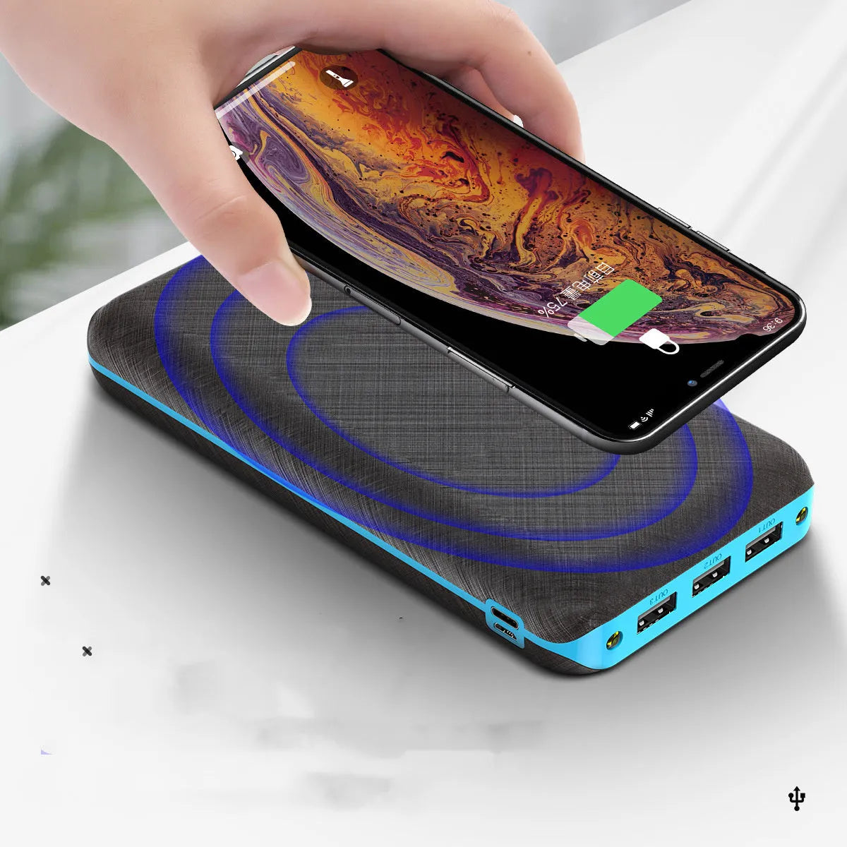 Black portable power bank with wireless charging surface and three USB ports for multiple device charging