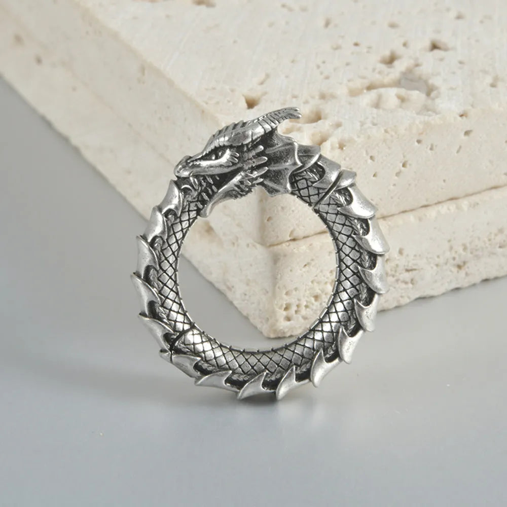 Large antique silver alloy earrings with a geometric hollow out dragon shape on a grey background.