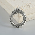 Large antique silver alloy earrings with a geometric hollow out dragon shape on a grey background.