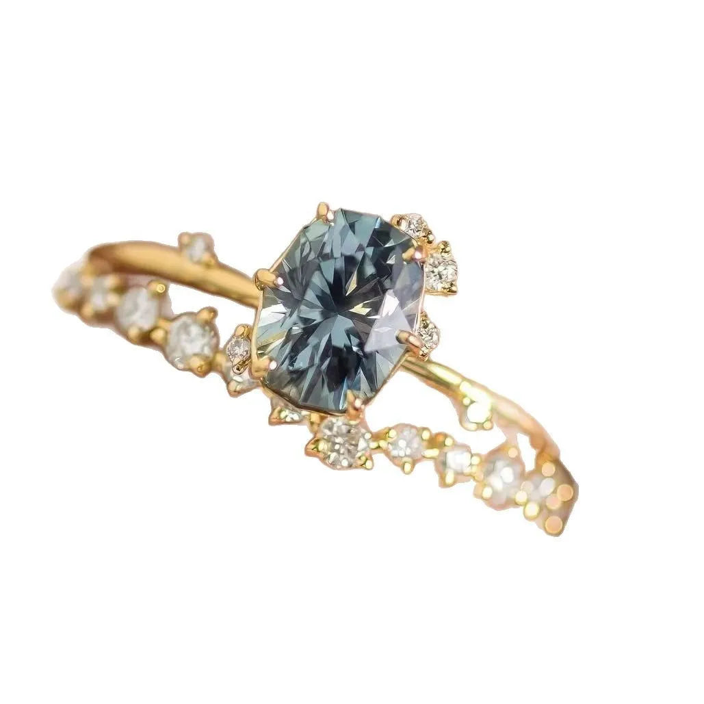 Gold-plated floral fashion ring with a central green zircon stone on a hand.