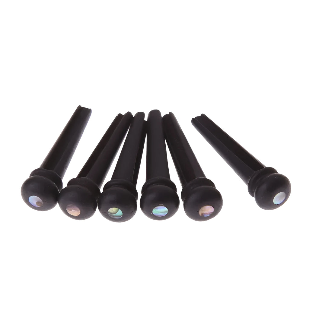 Six ebony guitar bridge pins with matt black finish on dark surface