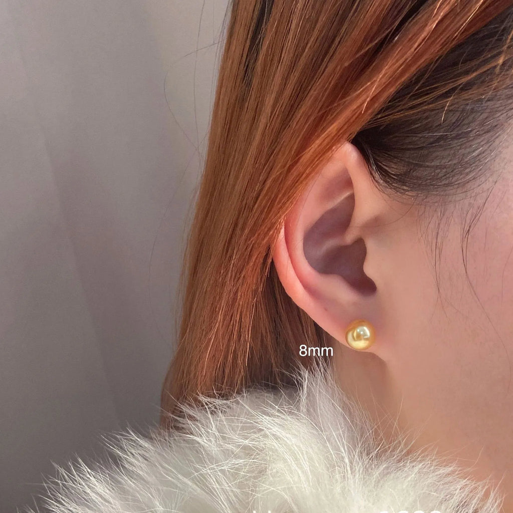 A pair of large pearl stud earrings with an eight-point star geometric setting in silver.