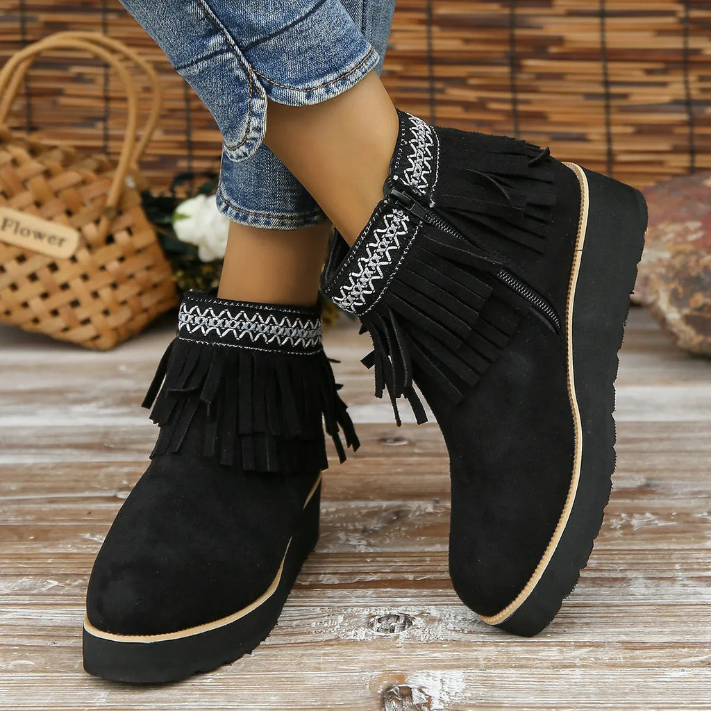 Women's black suede ankle boot with wedge heel, platform sole, side zip, and tassel detail.