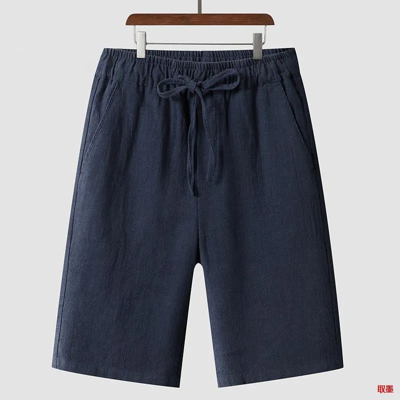 A pair of men's beige linen shorts with a loose, cropped cut and a mid-rise elasticated waistband.