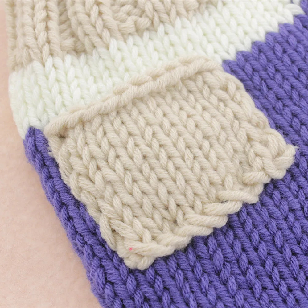 Handmade knitted wool baby photo suit in navy with hat and pants on a light background
