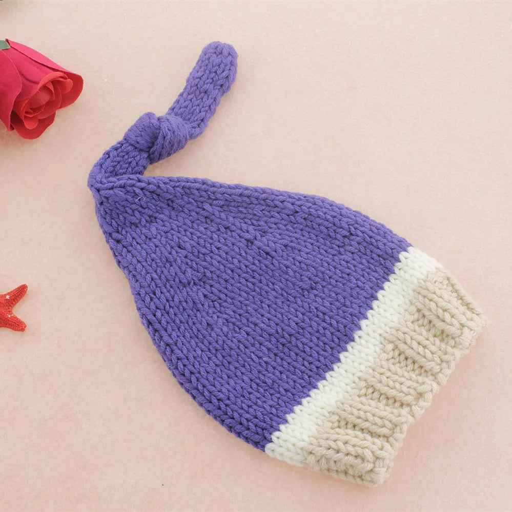 Handmade knitted wool baby photo suit in navy with hat and pants on a light background