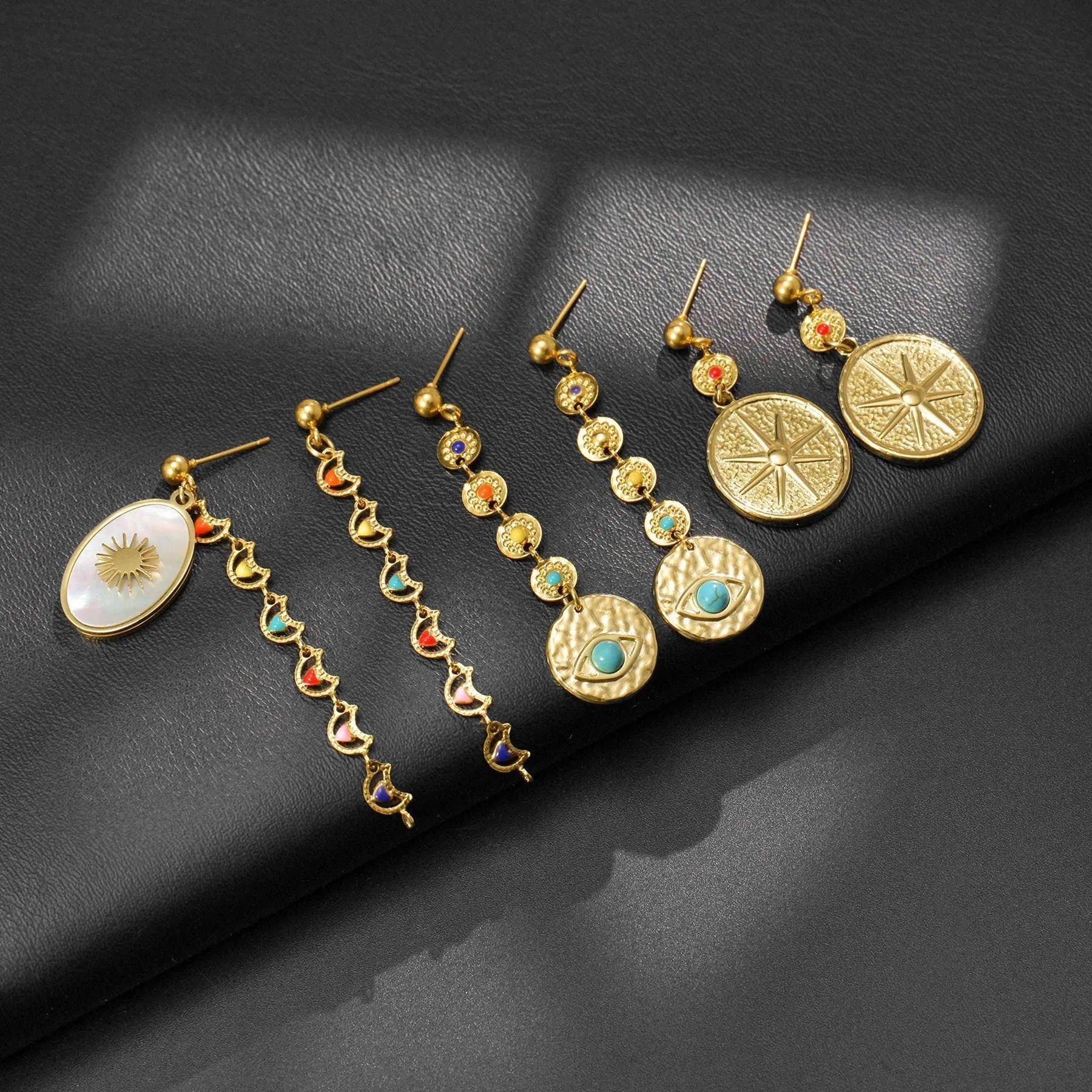 Three pairs of geometric stainless steel earrings showing star, eye and shell sun designs