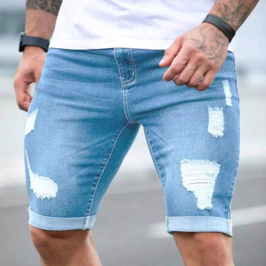 Sky blue men's denim shorts with a multi-hole distressed design on the front, showing a low waist and straight leg cut.