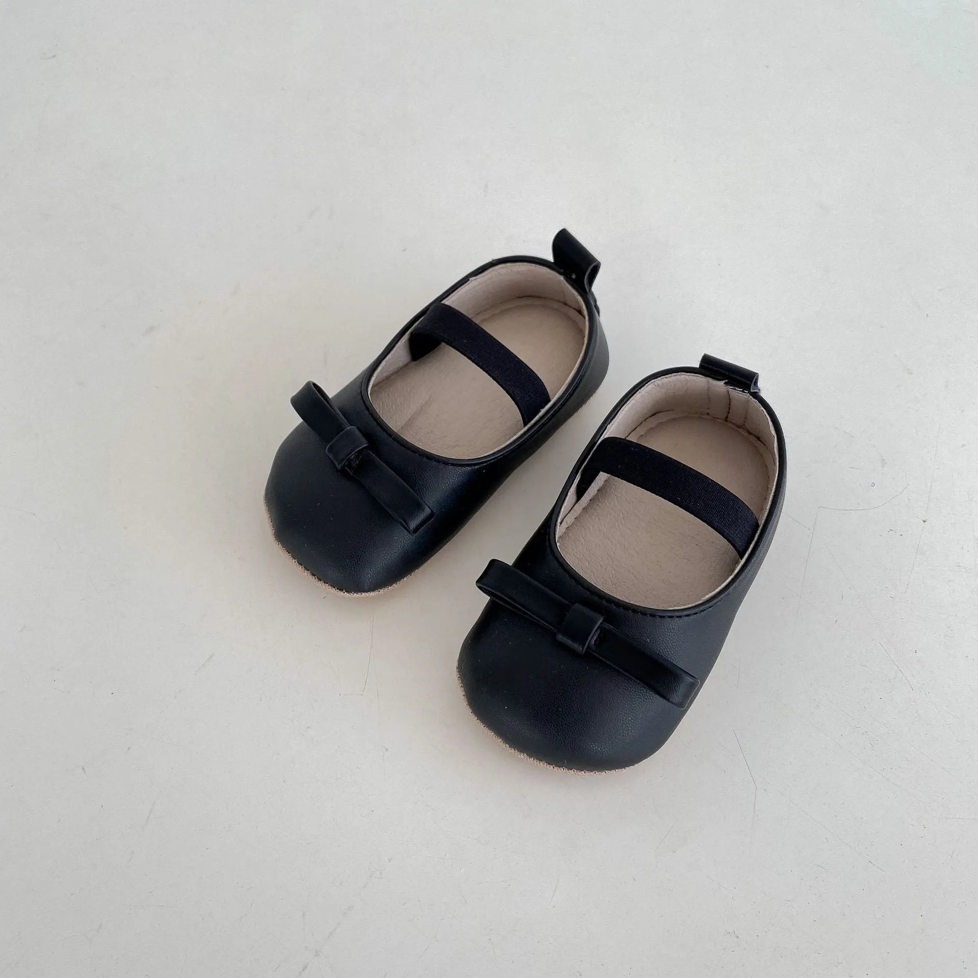 Baby shoes in white with bow detail, non-slip rubber sole, and elastic band fastening