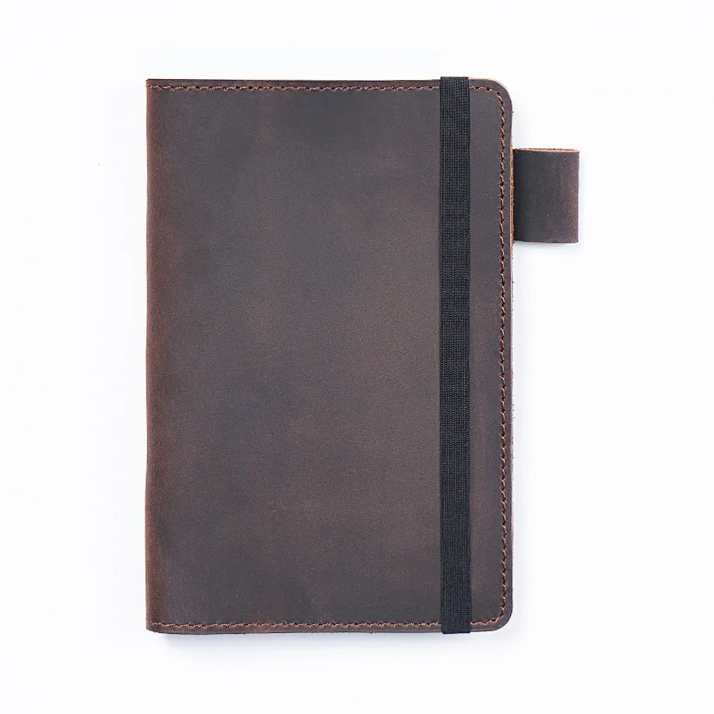 Handmade leather notebook in dark green, open on a desk showing wood-free paper pages.