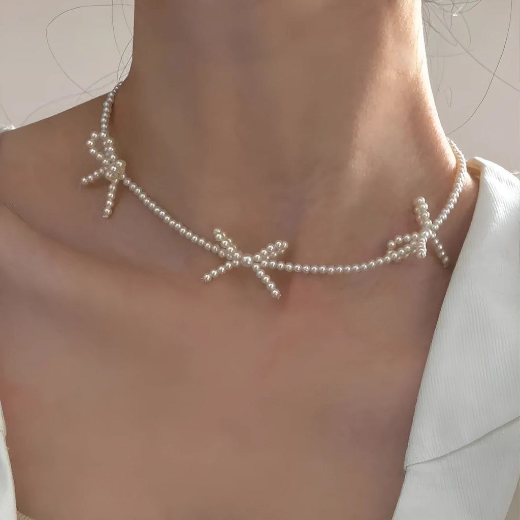 Women's white bow-shaped imitation pearl necklace with an adjustable chain.