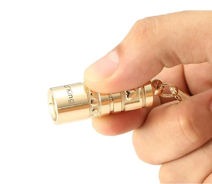 Gold zinc alloy waterproof mini LED flashlight on a keychain.