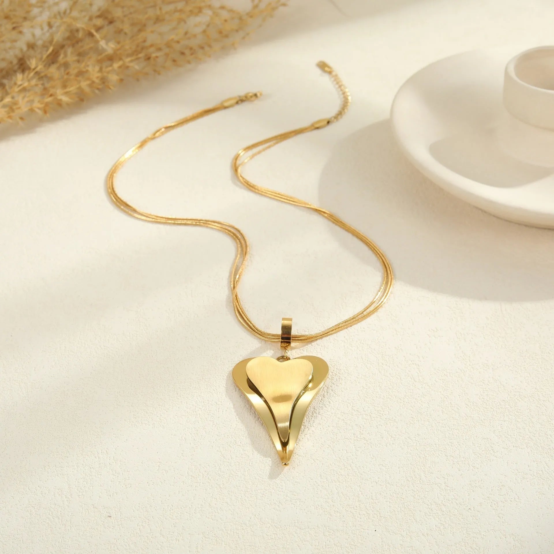 Geometric double heart pendant on a textured snake bones chain necklace in gold or steel finish.