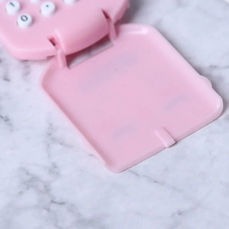 Creative cookie-shaped cute mini plastic calculator in black with key ring on a desk