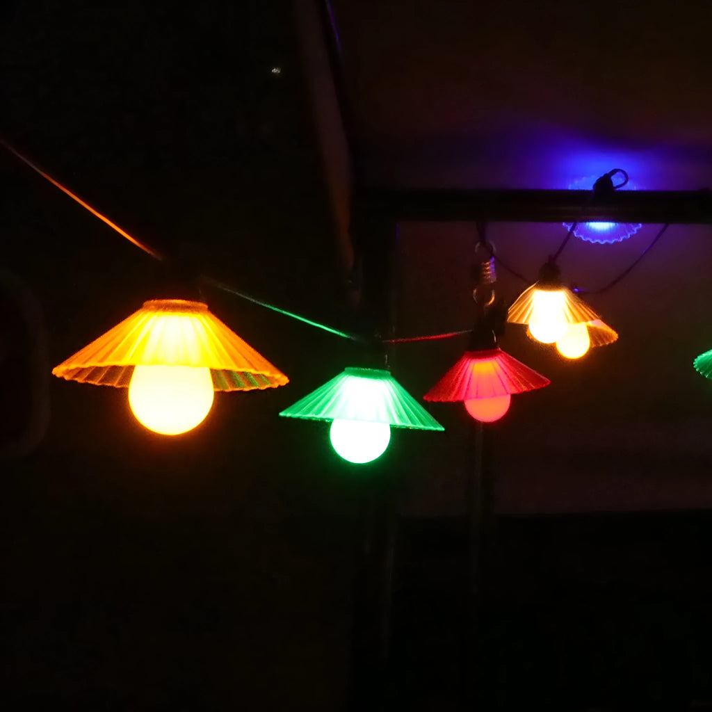 Outdoor LED string lights with flower-shaped bulbs hanging in a garden, showing warm white and coloured options.