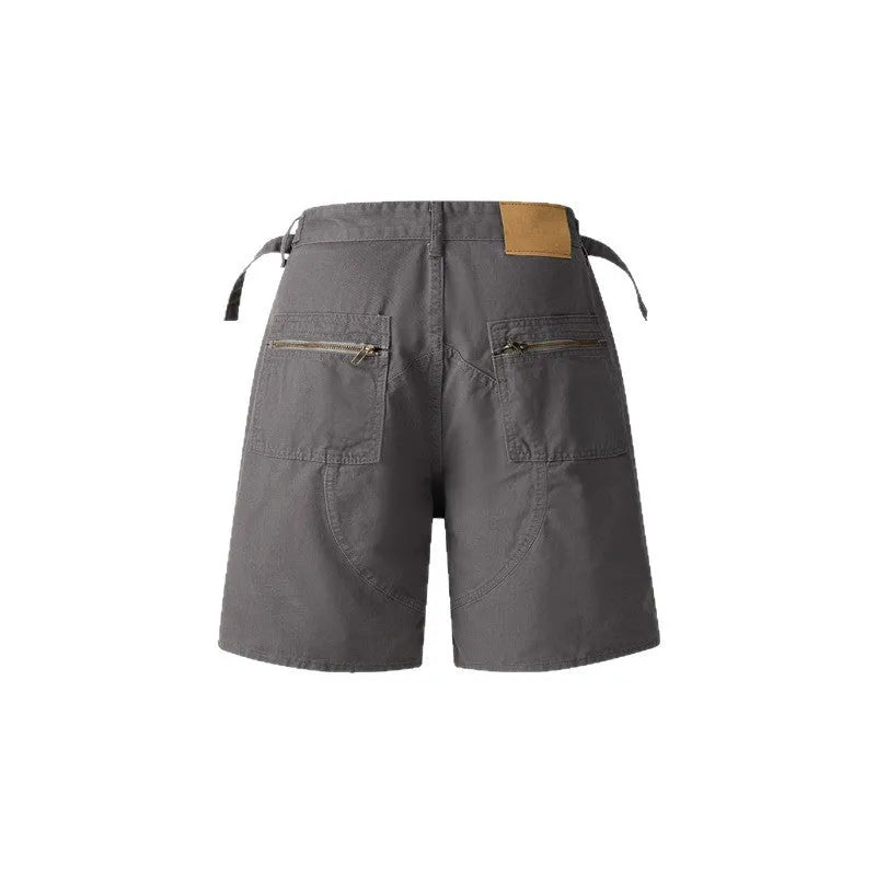 A pair of grey loose-fit cotton workwear shorts with a half-elastic waistband and side zipper on a neutral background.