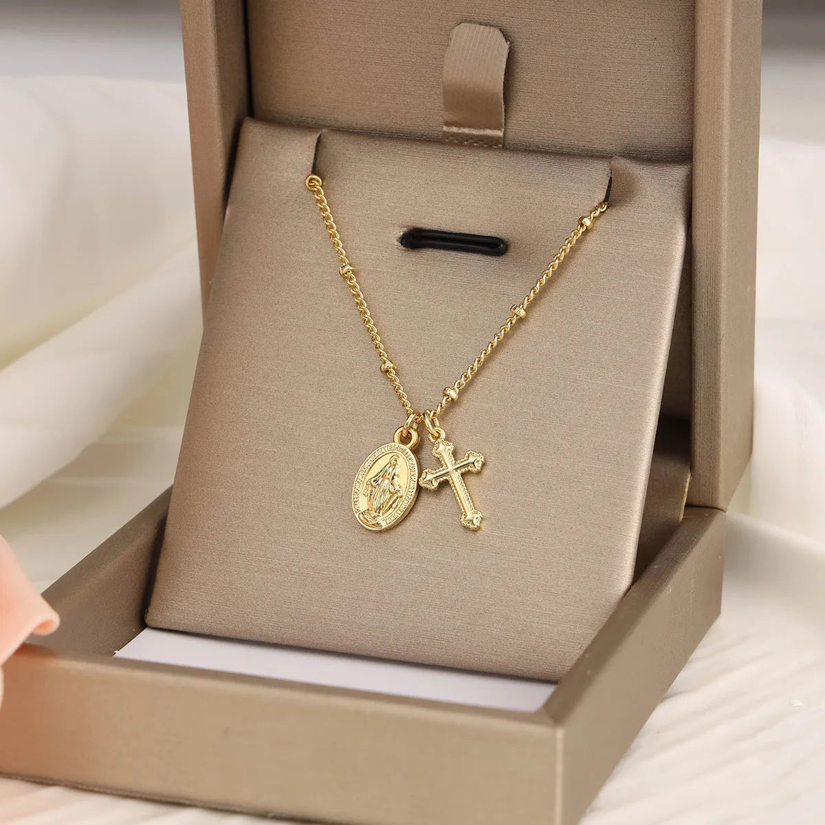 Gold-coloured copper necklace with a geometric cross pendant featuring a Virgin Mary centrepiece.