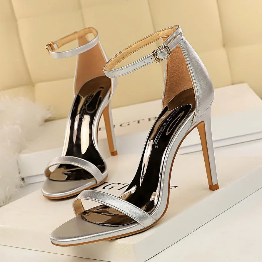 Women's open-toe high heel shoe with an ankle strap and buckle closure in a solid colour.