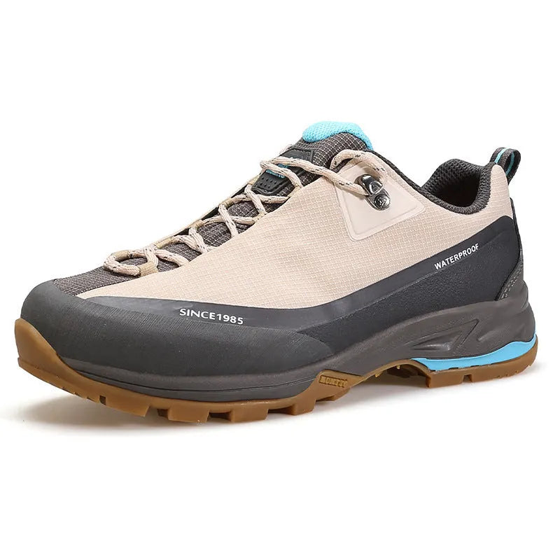Men's low-top hiking boots in dark grey with round toe and front lace-up design on a rocky trail.
