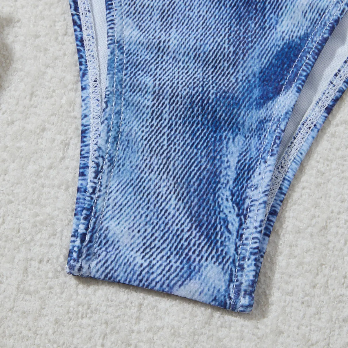 Women's denim blue printed bikini set with halterneck top and side-tie bottoms on a mannequin.