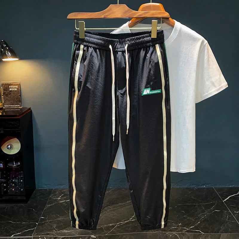 Men's black cotton harem-style casual trousers laid flat, showing relaxed fit and mid-waist design.
