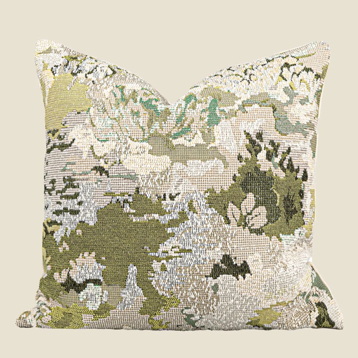 Green square pillow with abstract botanical plant and flower pattern on a sofa.