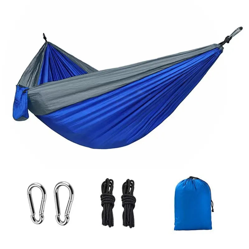 Large blue outdoor hammock made from parachute nylon fabric hanging between trees