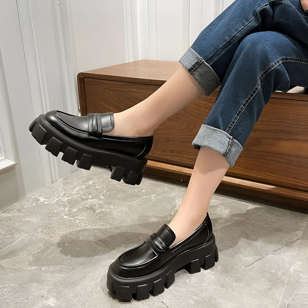A pair of wide fit patent leather loafers with a rubber sole and muffin heel base.