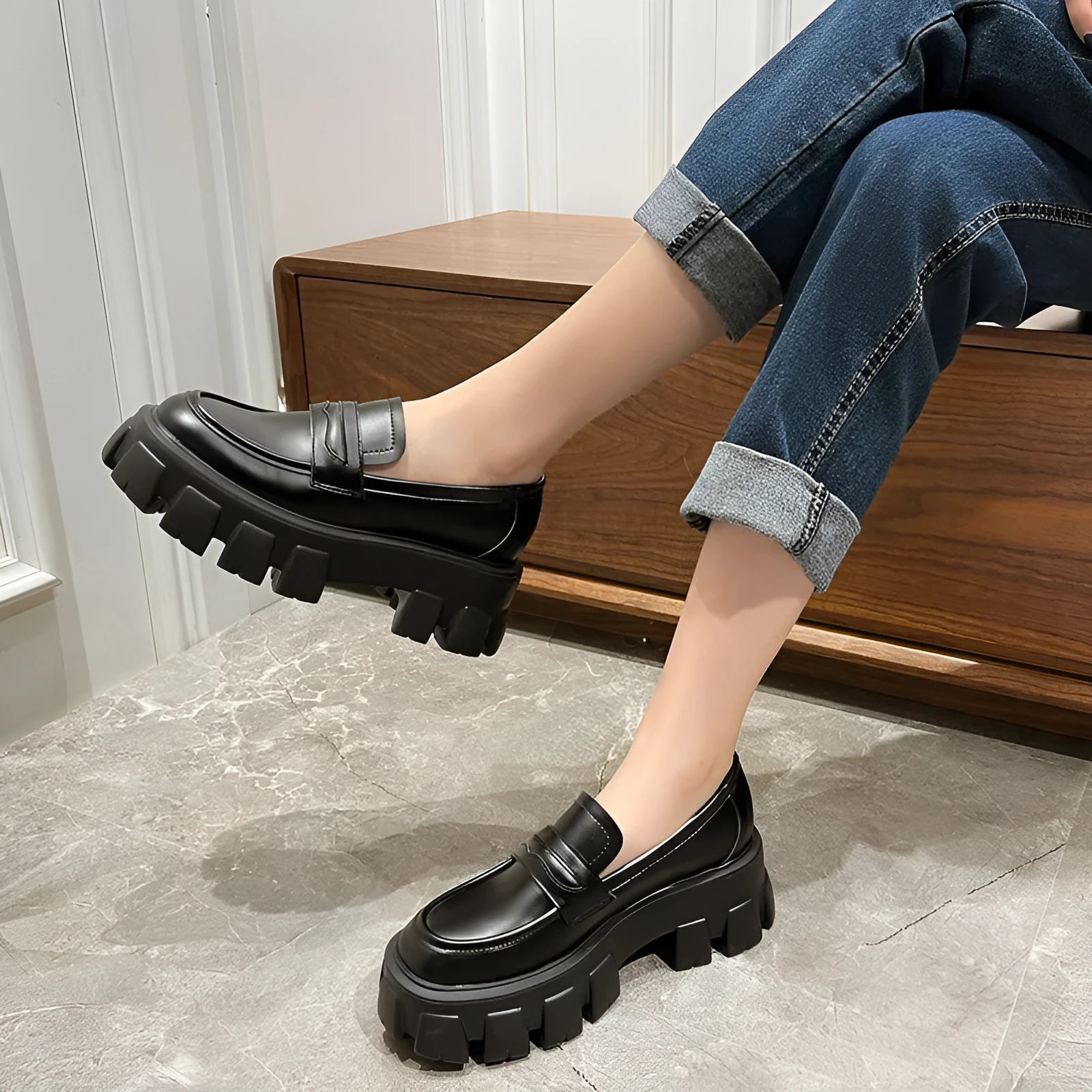 A pair of wide fit patent leather loafers with a rubber sole and muffin heel base.