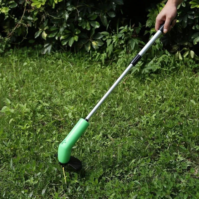 Cordless handheld lawn trimmer with extension pole and protective shield on green grass