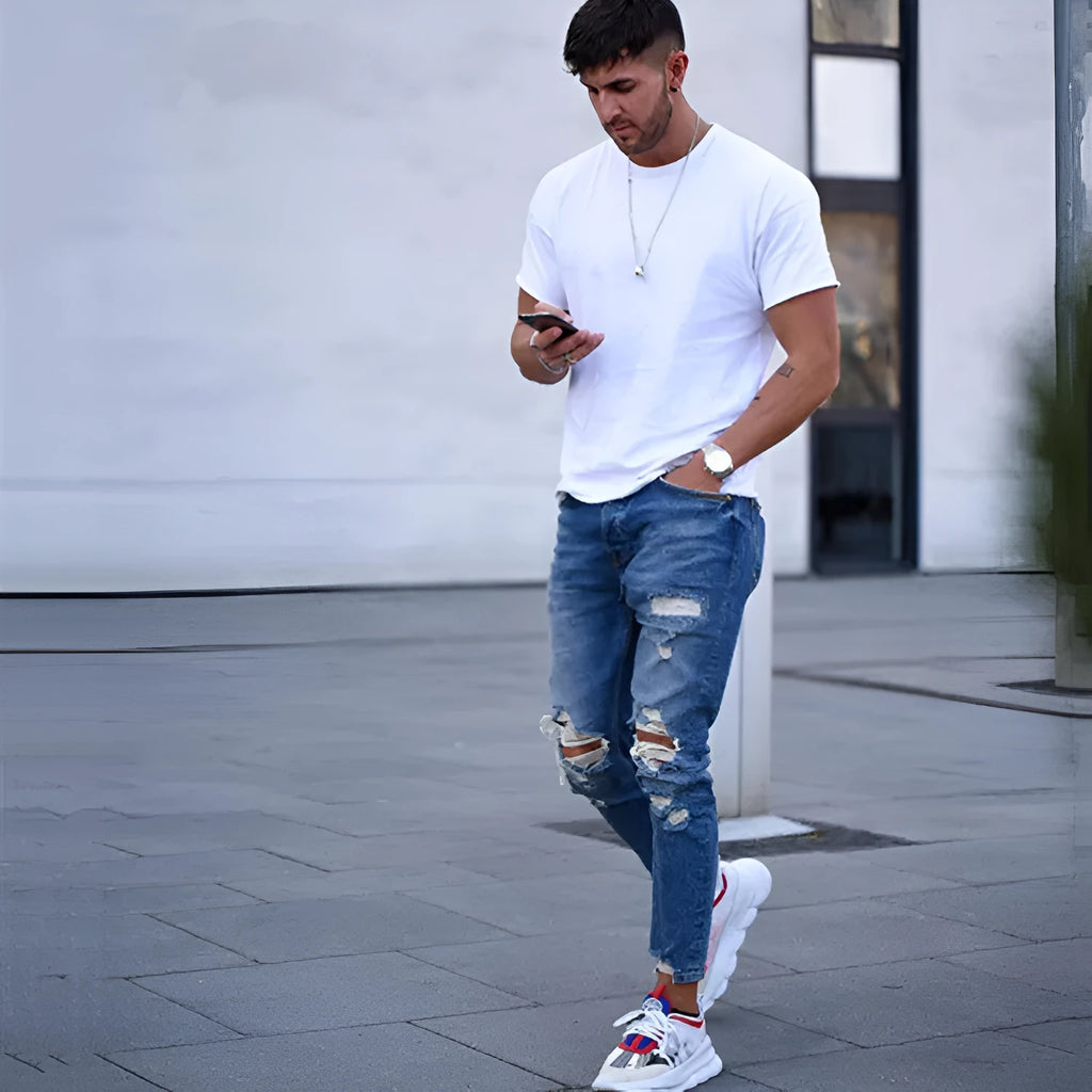 Deep blue men's jeans with distressed hole detailing on cotton fabric showing front and back views