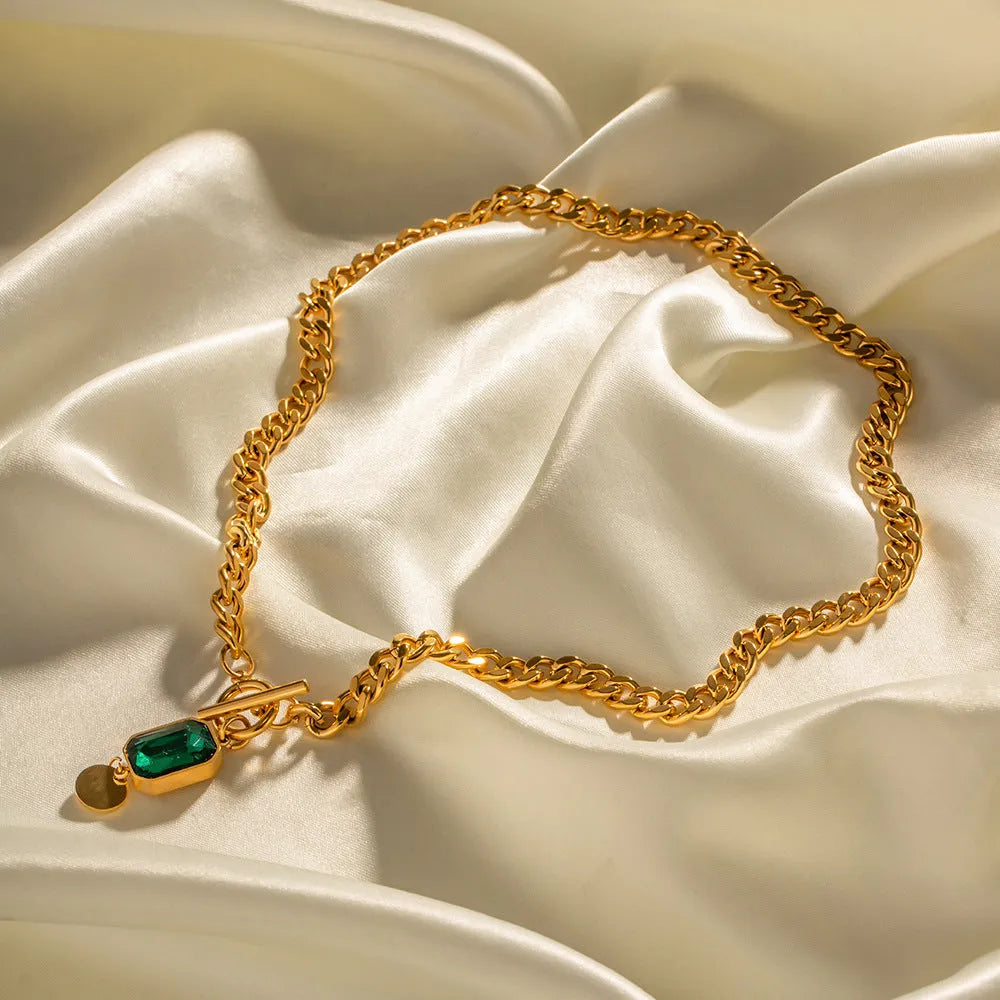 Gold electroplated titanium steel necklace with geometric round pendant containing emerald zircon accents