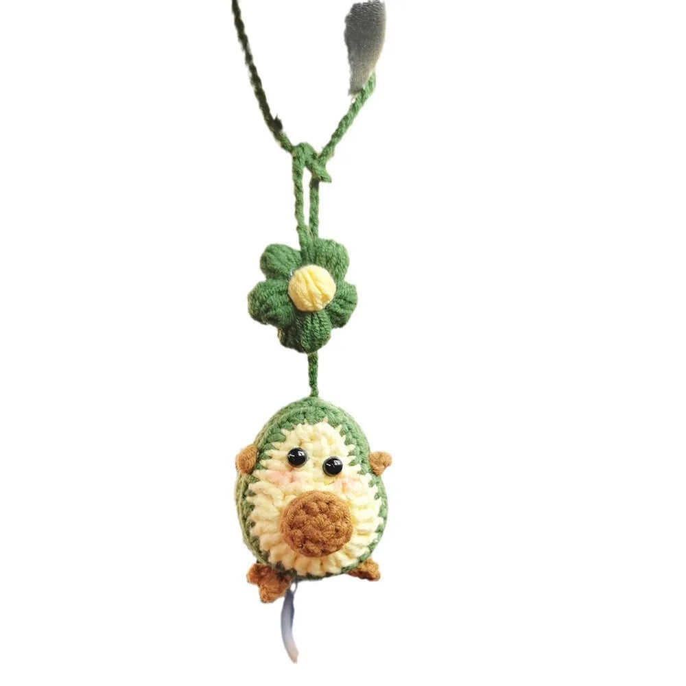 Handmade crocheted car pendant in avocado, pink rainbow, and red rainbow cartoon designs.