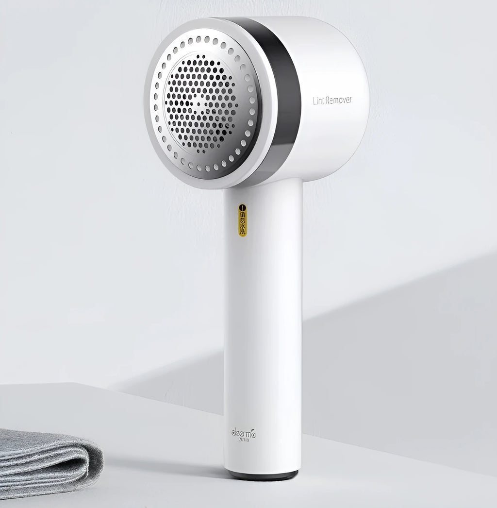 White rechargeable lint remover with three blades, hidden collection container, and ABS build on a plain background