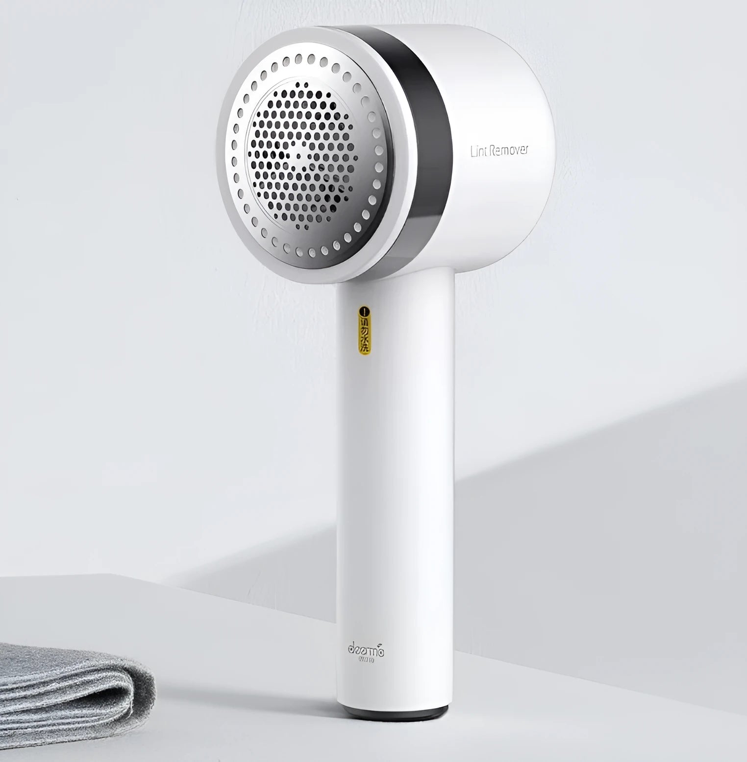 White rechargeable lint remover with three blades, hidden collection container, and ABS build on a plain background