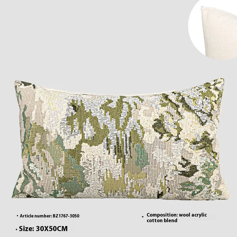 Green square pillow with abstract botanical plant and flower pattern on a sofa.