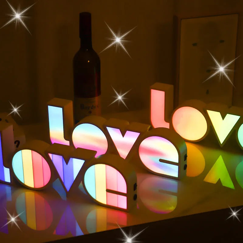 Rainbow-coloured plastic LED light spelling LOVE, standing 35.5cm tall on a table.