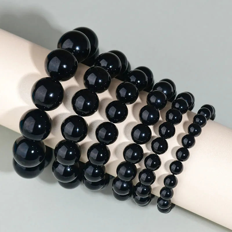 Hand-woven round obsidian bead bracelet for couples, showing colour options on a wrist.