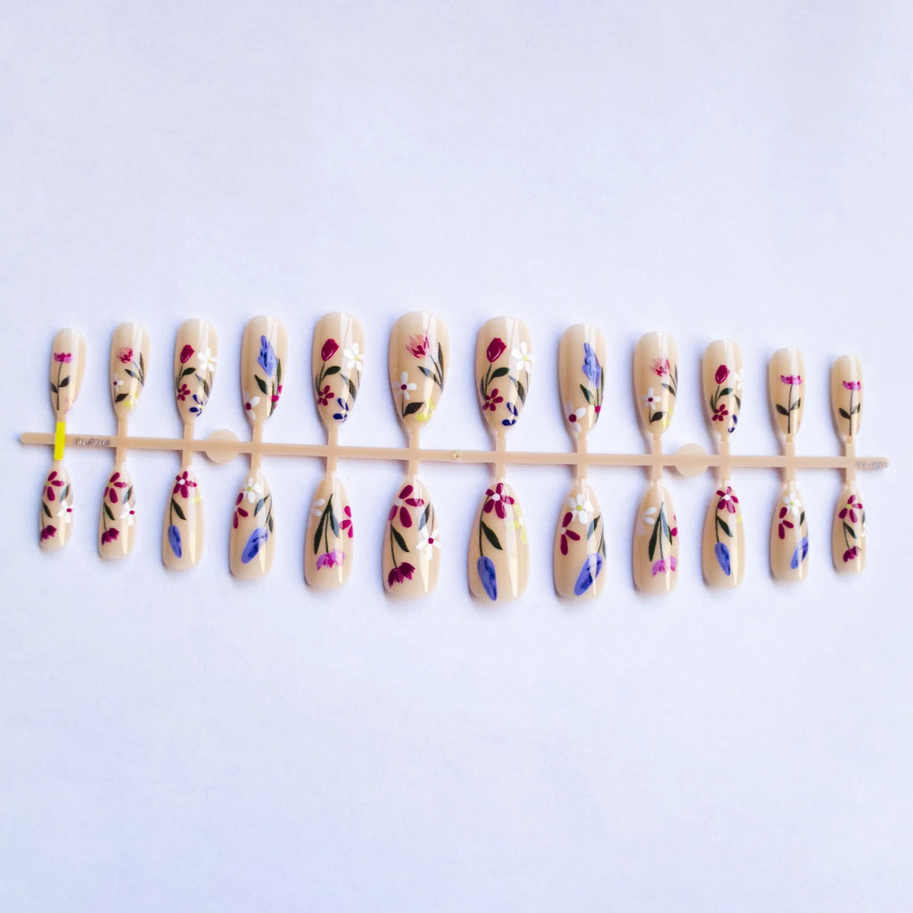 Almond-shaped removable false nails with rose and tulip floral designs on a solid colour background.