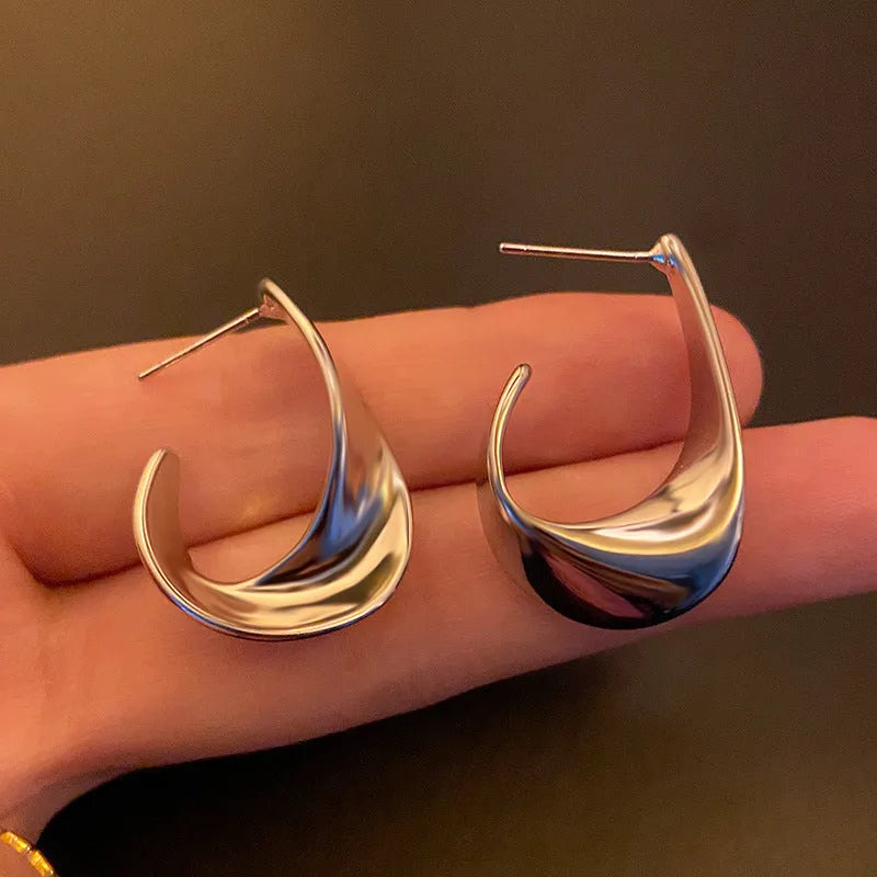 Gold and silver twisted geometric metal earrings with a round design element.