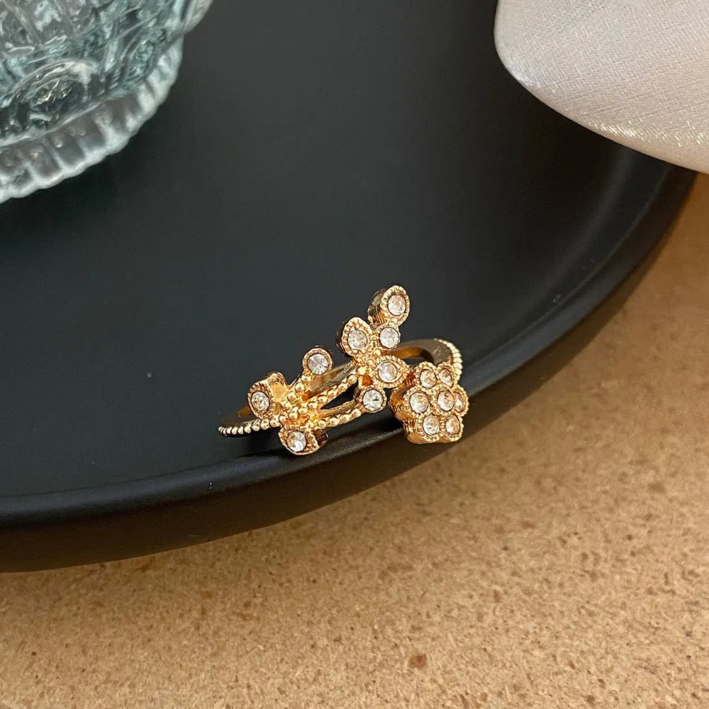 Women's open ring with flower and leaf design on a copper base with a diamond finish.
